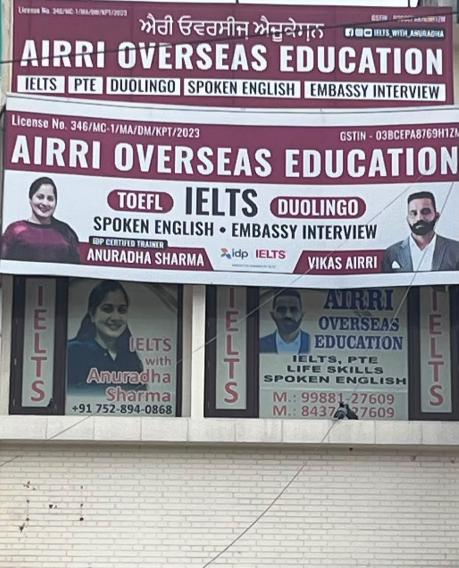 AIRRI Overseas Education signboard listing IELTS, PTE, Duolingo, Spoken English and Embassy Interview with IDP certified trainers Anuradha Sharma and Vikas Airri